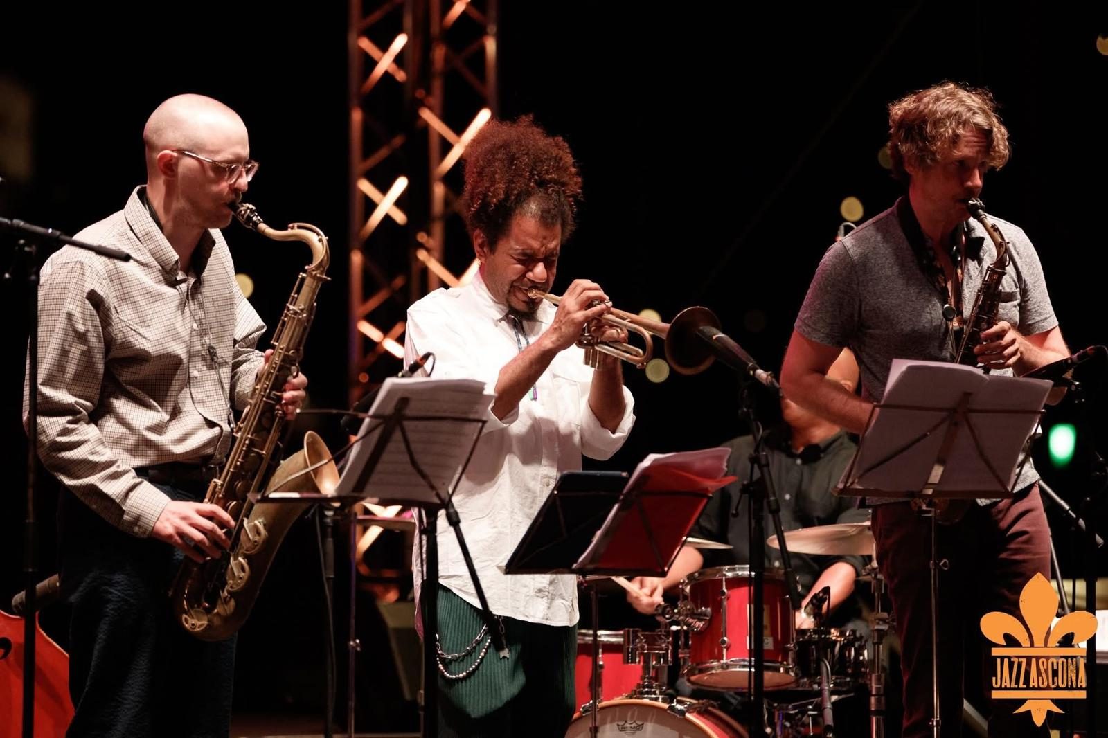 Tenor saxophone, trumpet and alto saxophone players reading charts on stage