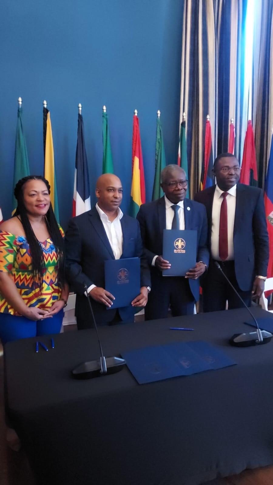 Partners holding signed agreements in front of a row of national flags