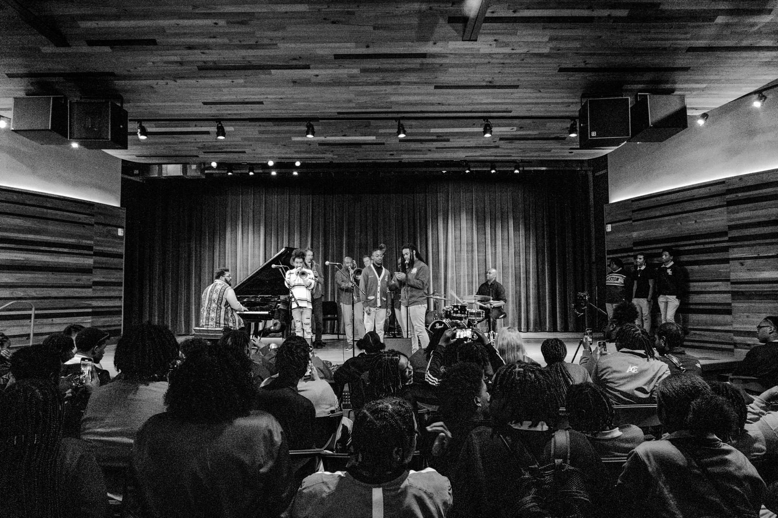 A packed hall of students watching NOJI musicians and young singers perform
